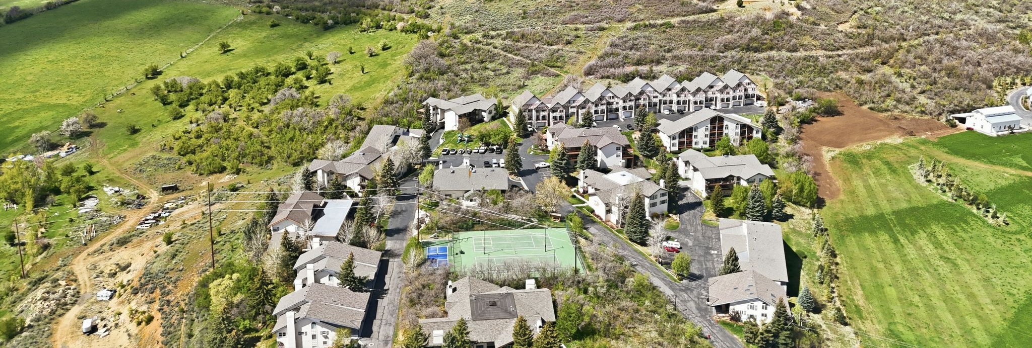 Aerial view of Swiss Oaks community in Midway Utah with townhome rooftops and Wasatch mountain backdrop