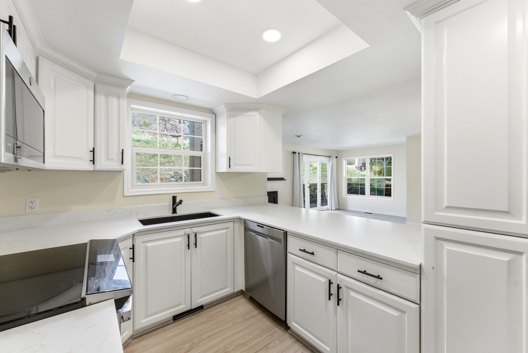 Remodeled white kitchen with quartz-look counters and tray ceiling in Midway Swiss Oaks condo